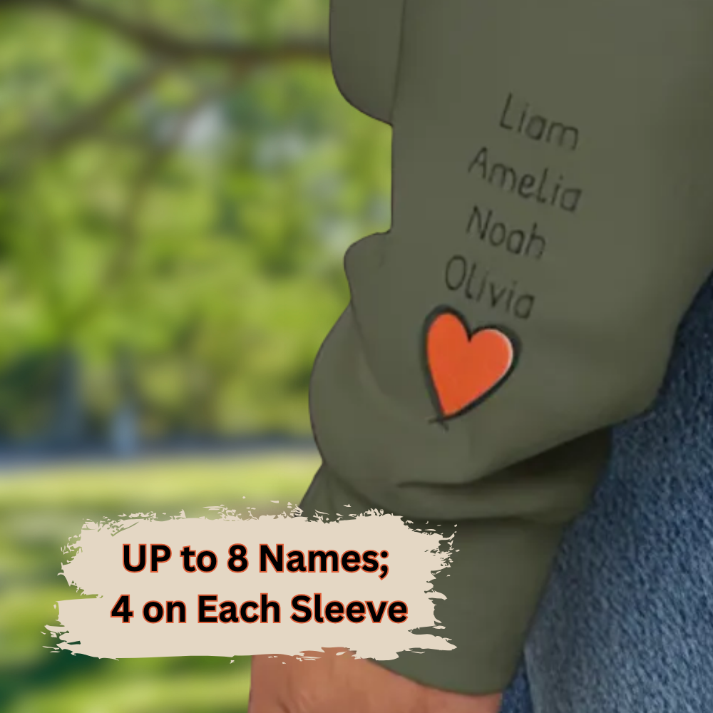 Children's shirt with names embroidered on each sleeve against a blurred green outdoor background