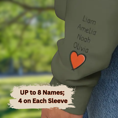 Children's shirt with names embroidered on each sleeve against a blurred green outdoor background